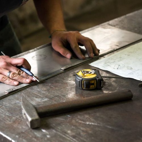 Metalworker marking measurements on metal